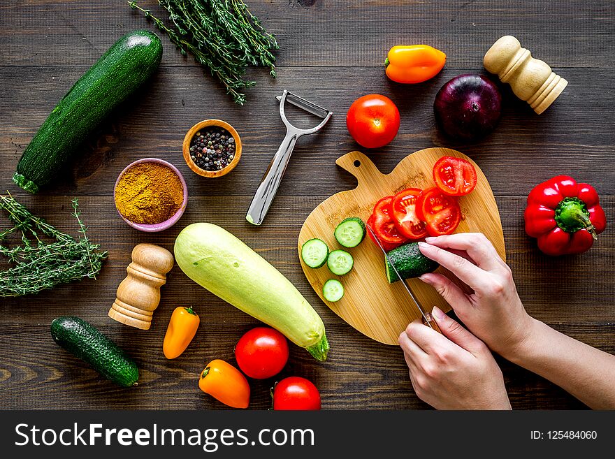 Cut different fresh vegetables on cutting board for cooking vegetable stew. Dark wooden background top view.