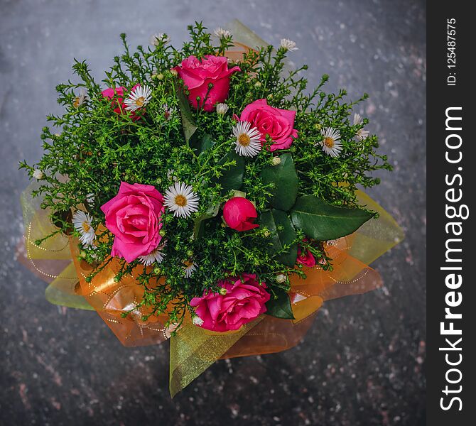 Beautiful Bouquet Of Red And White Flowers With Green Plants On A Black Stone Table. The View From The Top. Flat Lay.