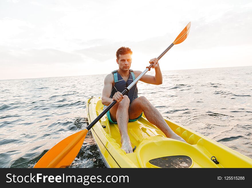Handsome man kayaking on lake sea in boat.