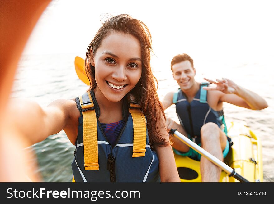 Loving couple kayaking on lake sea in boat make selfie by camera.