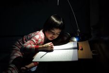 Portrait Of Little Asian Girls Doing Her Homework Under The Lighting Lamp Royalty Free Stock Images