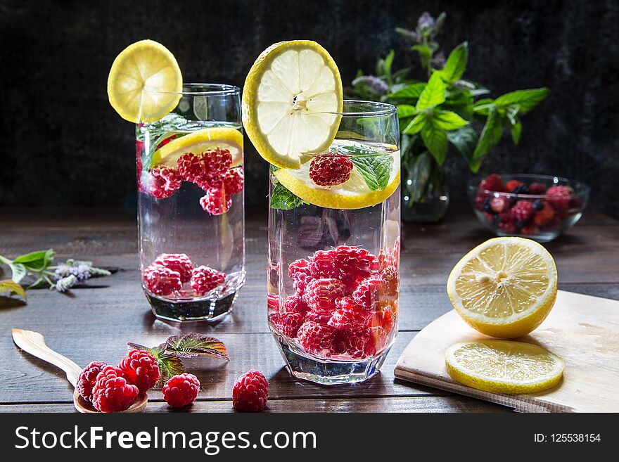Refreshing drink with raspberries, lemon and mint on a dark background. Refreshing drink with raspberries, lemon and mint on a dark background.
