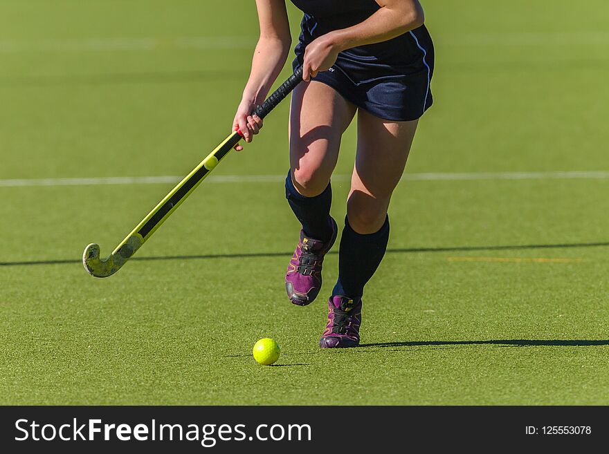 Hockey action abstract photo of unidentified girl player running legs ball and stick on astro turf. Hockey action abstract photo of unidentified girl player running legs ball and stick on astro turf.