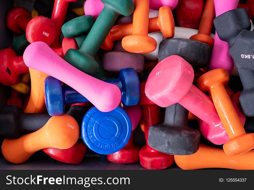 Many colorful dumbbells in a box. Fitness studio theme objects