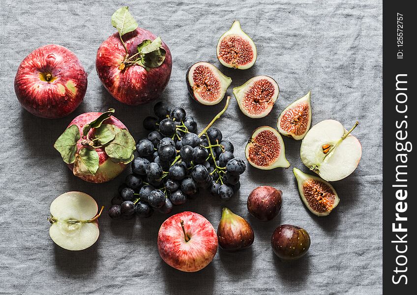 Seasonal autumn fruits - apples, grapes, figs on a gray background, top view.