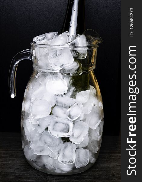 Wine or champagne bottle in glass pitcher with ice isolated on black background