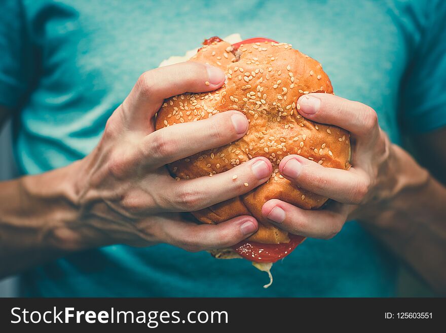 Big sandwich - hamburger burger with beef, cheese, tomato and tartar sauce in female hands. Big sandwich - hamburger burger with beef, cheese, tomato and tartar sauce in female hands