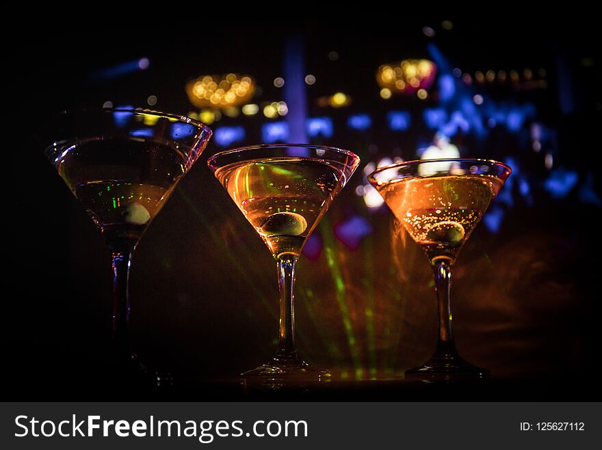 Several Glasses Of Famous Cocktail Martini, Shot At A Bar With Dark Toned Foggy Background And Disco Lights. Club Drink Concept