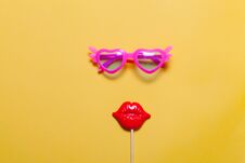 Holiday Minimalistic Flat Lay: Funny Pink Sunglasses And Masquerade Plastic Lips On Stick. Yellow Background Stock Photography