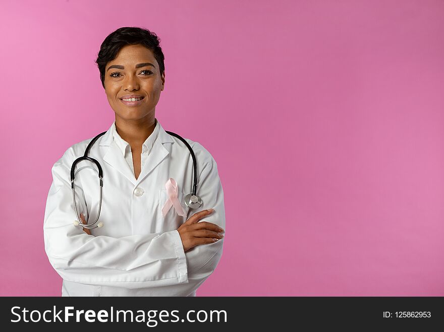 Smiling nurse wearing breast cancer awareness ribbon