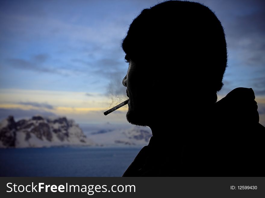 Silhouette of male smokers in the background of the mountains of Antarctica