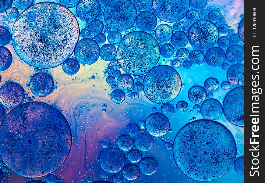 Macro of oil drops and pigment on water surface with bright background. Macro of oil drops and pigment on water surface with bright background