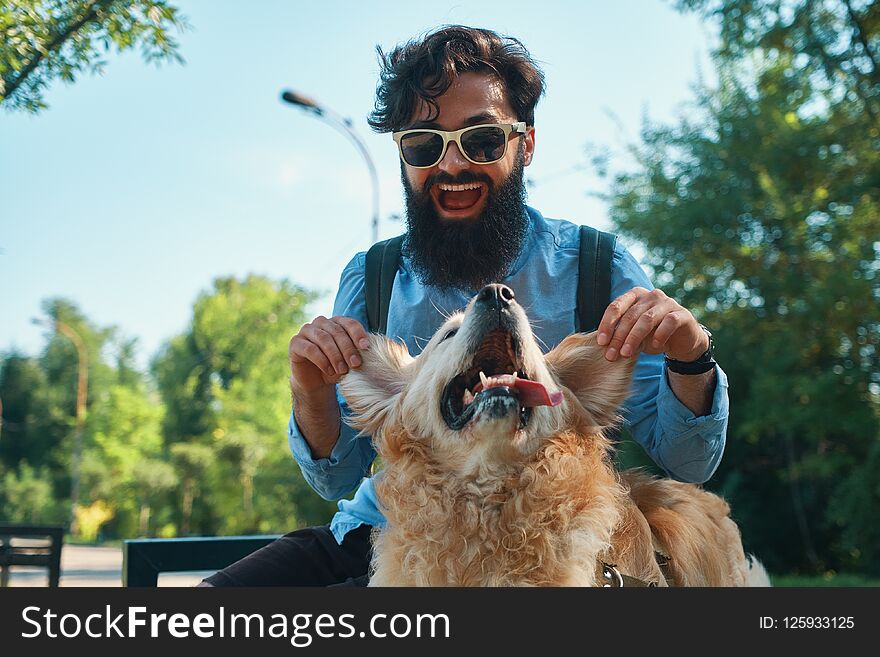 Man and dog having fun, playing, making funny faces while resting in the park. Life is beautiful, best friends concept.