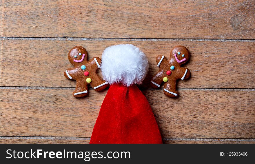 Gingerbread cookie and Santa Claus hat on wooden table