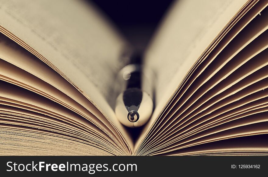 Close-up of a silver pen in the open pages of an old book