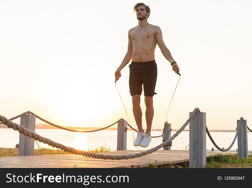 Portrait Of Muscular Young Man Exercising With Jumping Rope