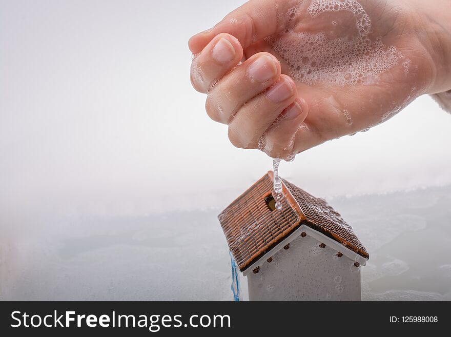 Hand holding a model house in foamy water. Hand holding a model house in foamy water