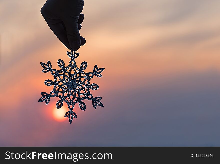 Sparkling huge snowflake on a sunset sky background. Winter and Christmas concept.