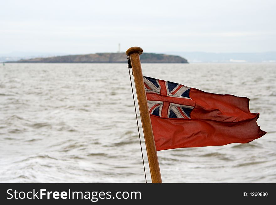 A Red Ensign flies from the back of a ship. A Red Ensign flies from the back of a ship