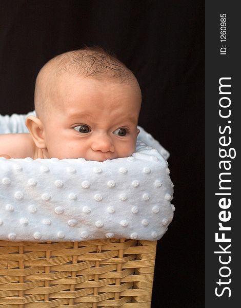 Image of a cute baby boy sitting in a blanket-lined basket. Image of a cute baby boy sitting in a blanket-lined basket