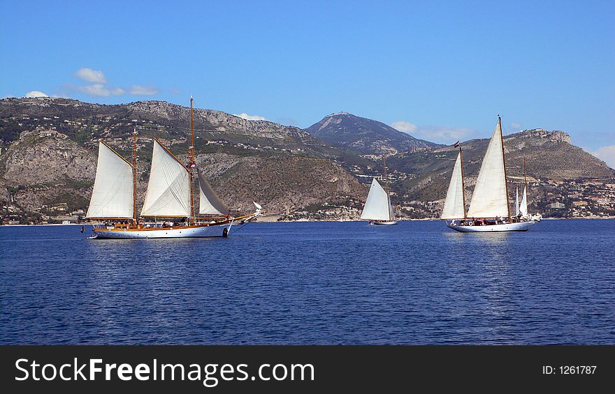Three classic sailing yachts hoisting sails to make their get away. Three classic sailing yachts hoisting sails to make their get away.