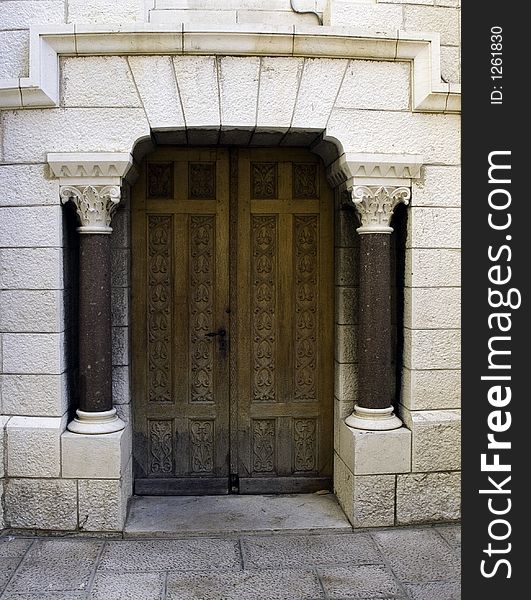 Antique chisseled wooden door in marble ans natural stone surround
