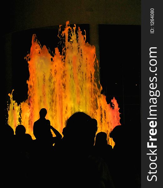 People silhouettes on multicolored fountain