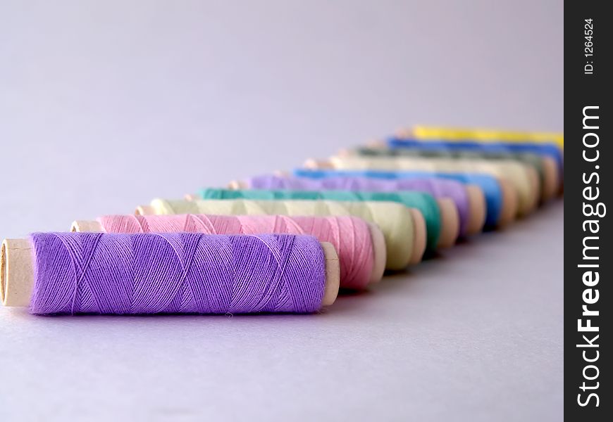 Colored sewing threads on light background