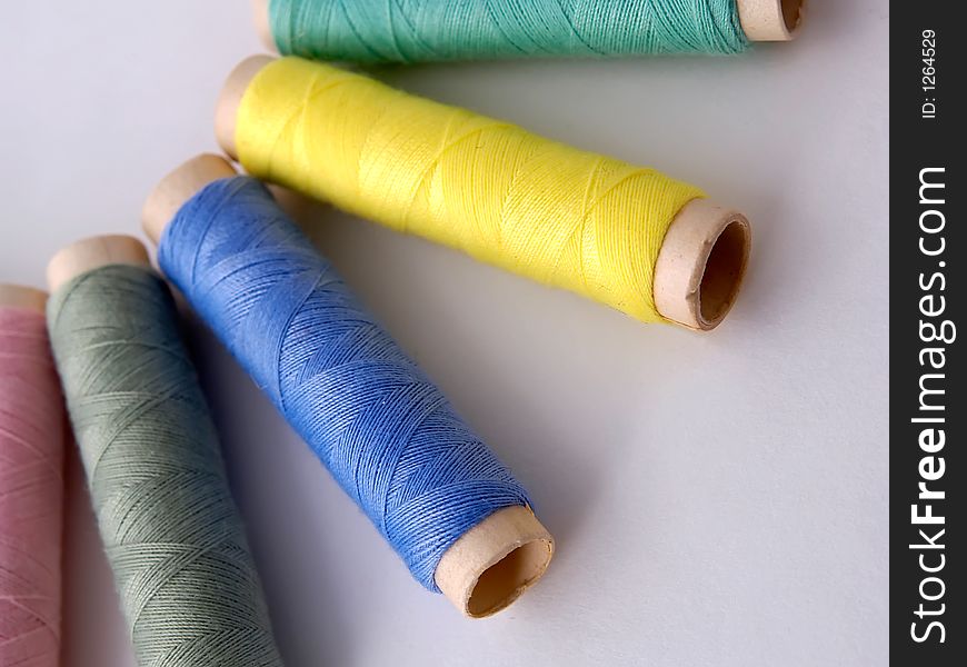 Different color sewing thread on light background