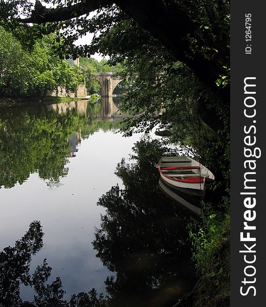 One small boat in a river, under a tree. One small boat in a river, under a tree