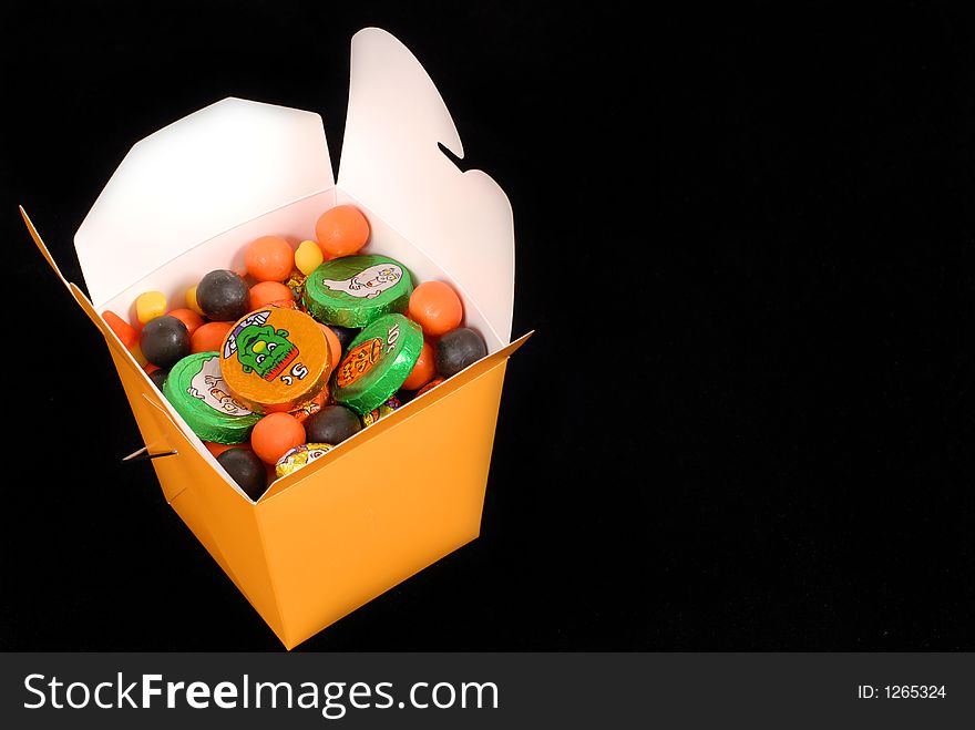 Halloween candy in an orange chinese food container isolated on black