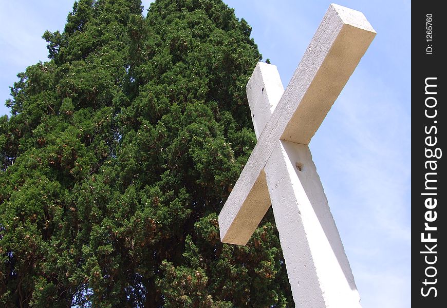 Stone cross and cypress with blue sky