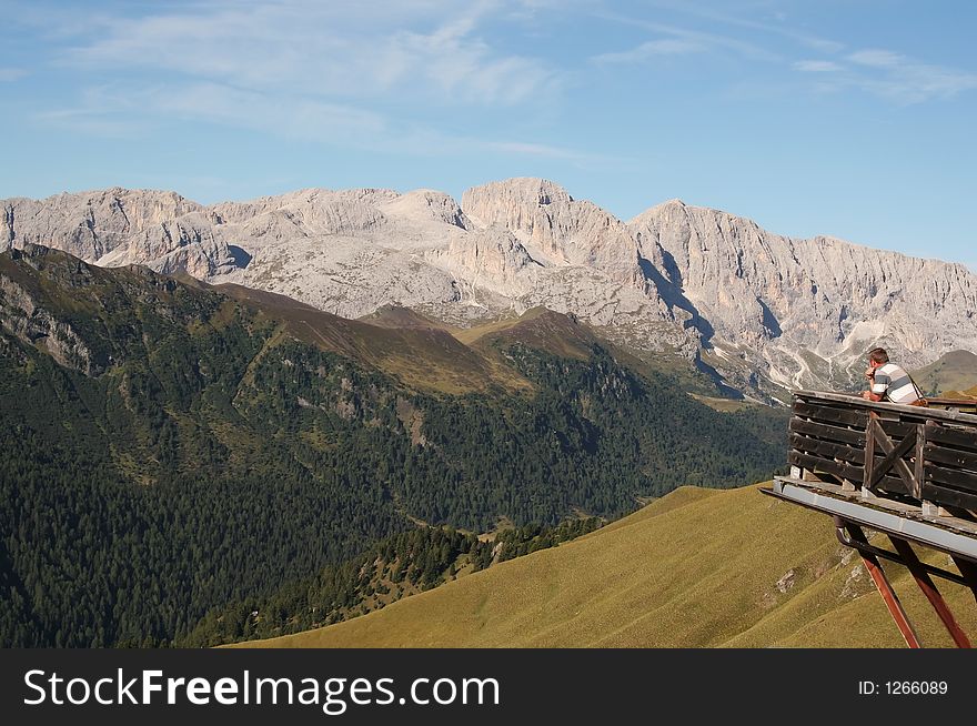 Man admires mountain scene from high vantage point. Man admires mountain scene from high vantage point