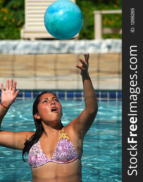 A girl is passing a ball in the pool. A girl is passing a ball in the pool