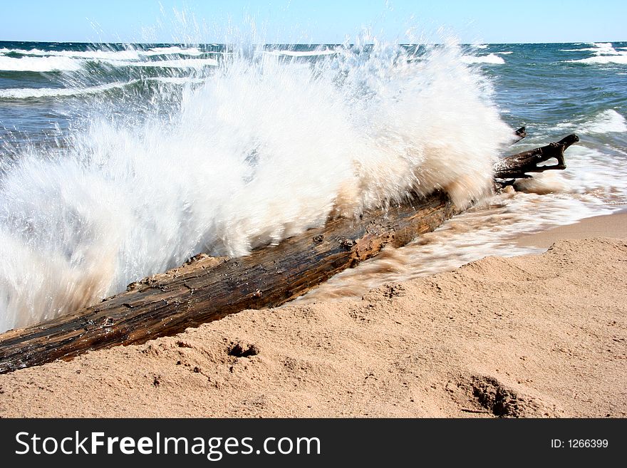 A wave crashes into a beached log. A wave crashes into a beached log