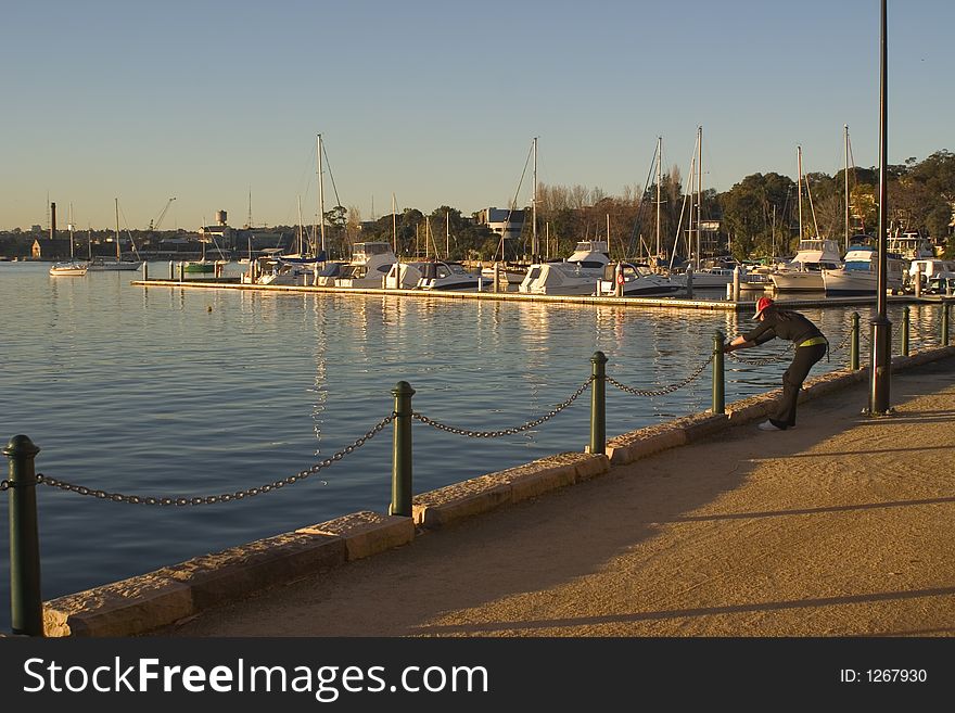 A girl stretching on a waterside run. A girl stretching on a waterside run