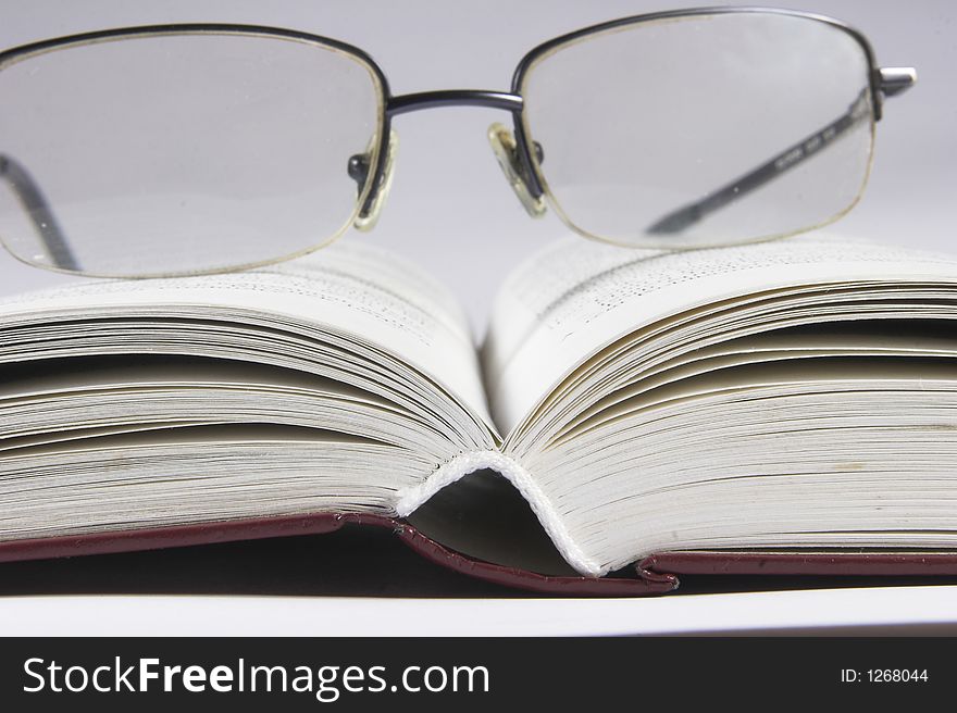 Eyeglass on book with white background