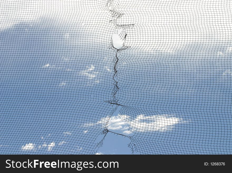 A photograph taken of a ripped net against the blue sky. A photograph taken of a ripped net against the blue sky.