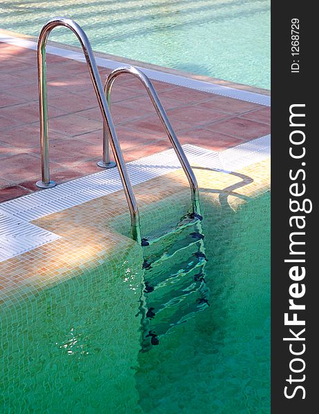 Steps leading out of clear green swimming pool