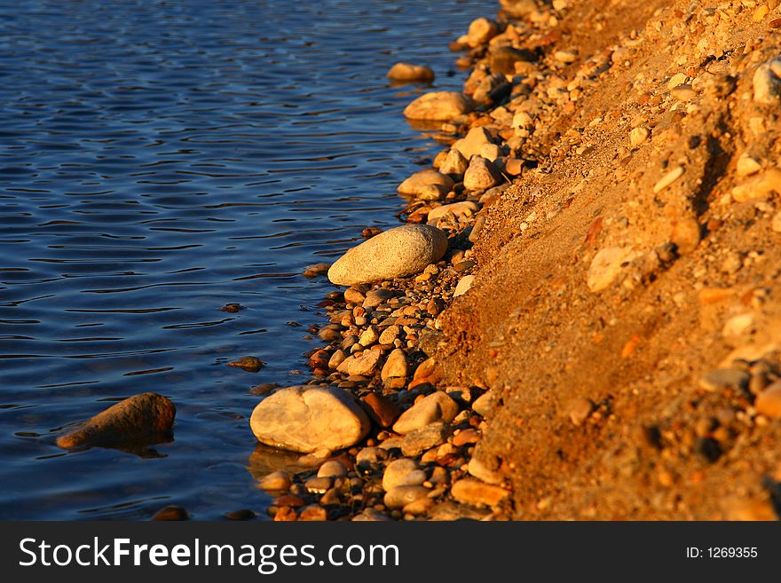 Stones by the lake bank, in sunset light