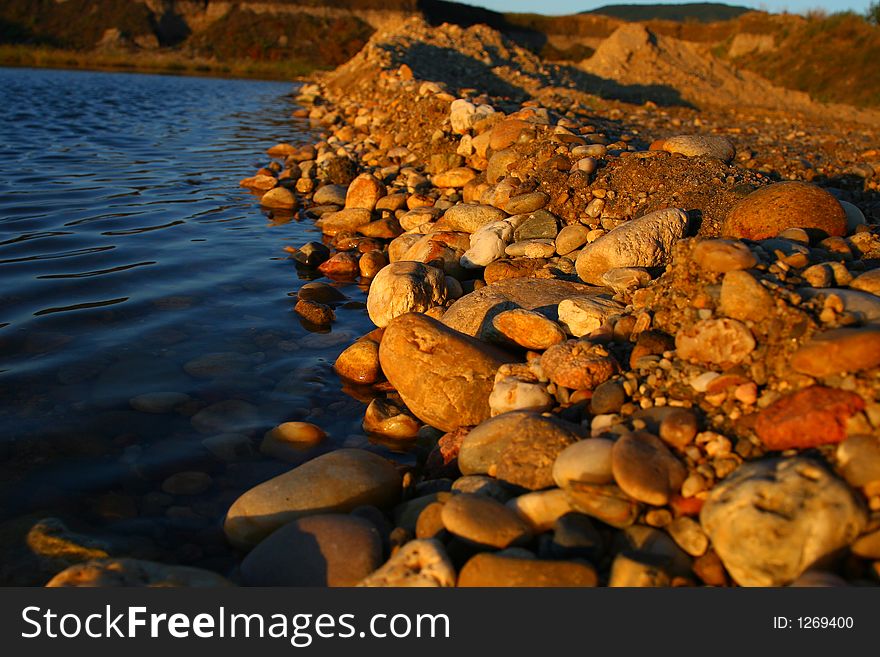 Stones by the lake bank, in sunset light