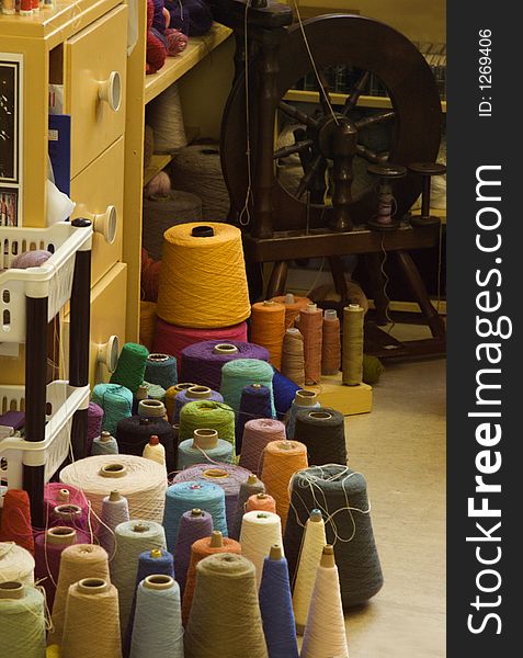 Spinning wheel and colorful yarns in a studio. Spinning wheel and colorful yarns in a studio