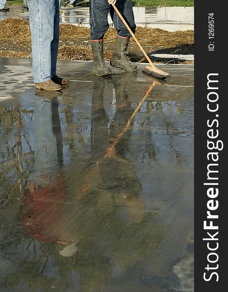 Two workers at a construction site reflected in wet concrete- room for text at bottom. Two workers at a construction site reflected in wet concrete- room for text at bottom