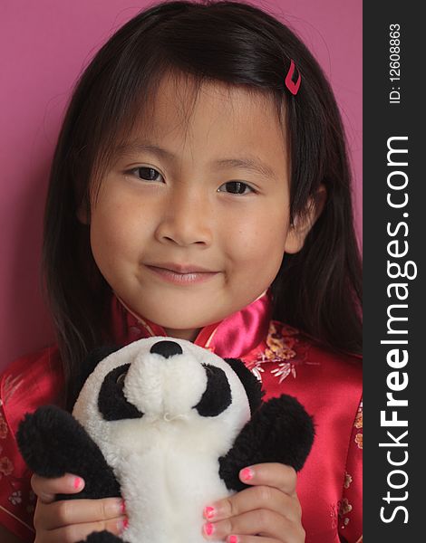 Little asian chinese girl holding a panda bear with a red silk dress on. Little asian chinese girl holding a panda bear with a red silk dress on