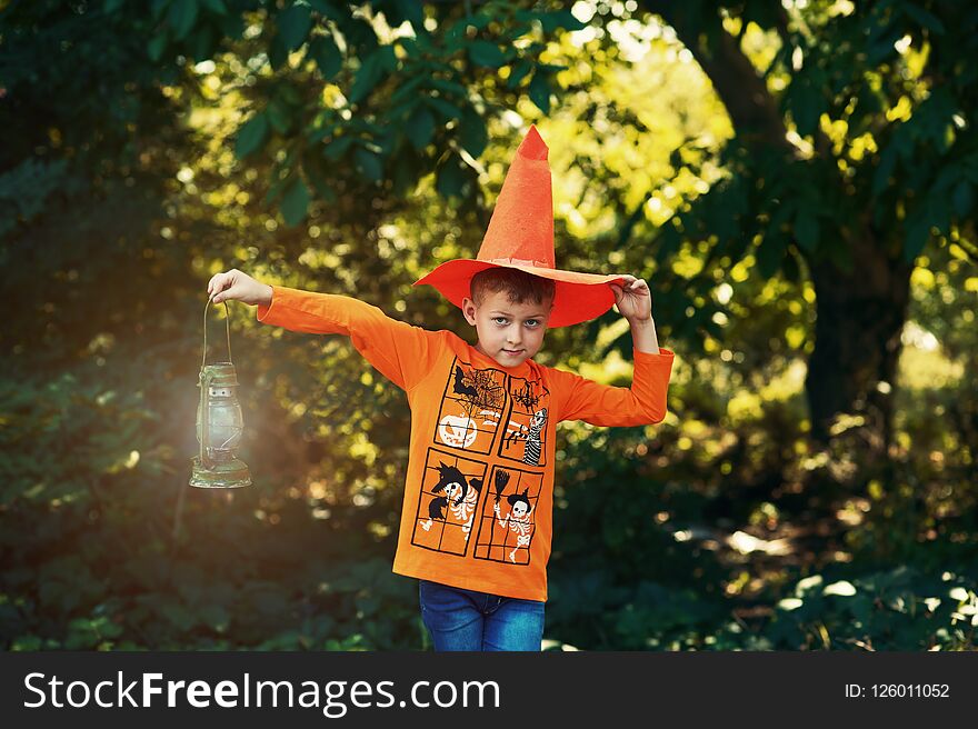 A Boy In A Hat On Halloween With A Lantern In His Hands