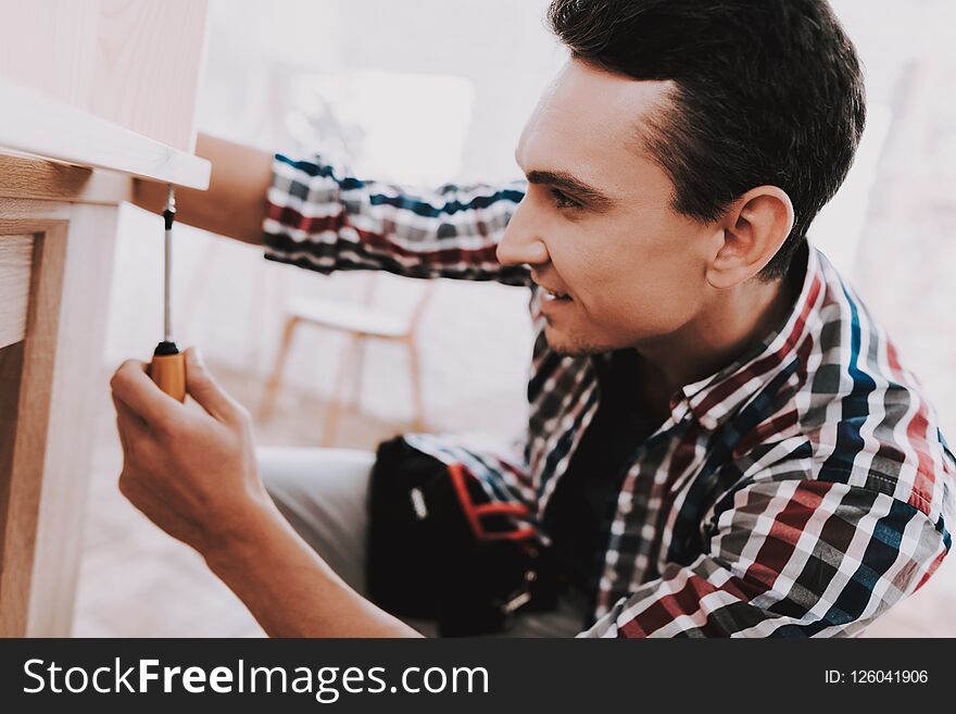 Young Man Assembling Wooden Bookshelf at Home. Wooden Bookcase. Selfmade Furniture. Man and Hobby. White Room. Engineer with Tool. Young Man at Home. Homemade Decoration. Modern Furniture.