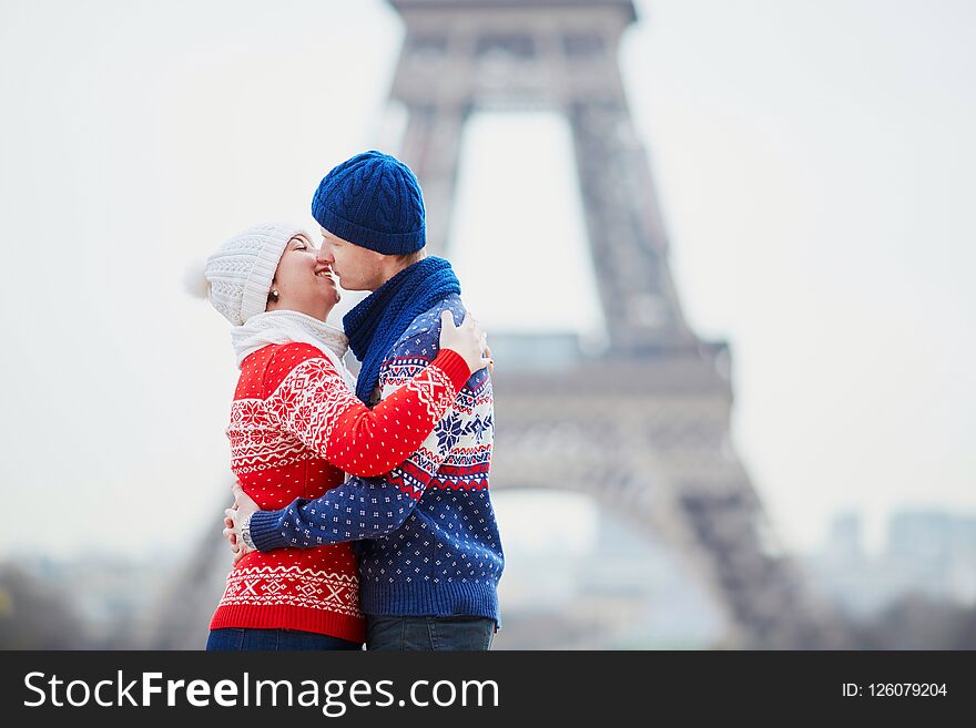Happy couple near the Eiffel tower on a winter day. Trip to Paris during season holidays