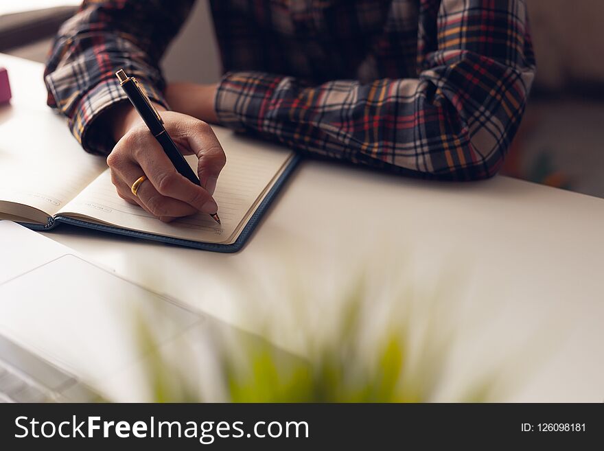 The man is writing a message in the book on table. He is now sitting business plan that has new idea in the morning. Concept idea planing and analyzes.