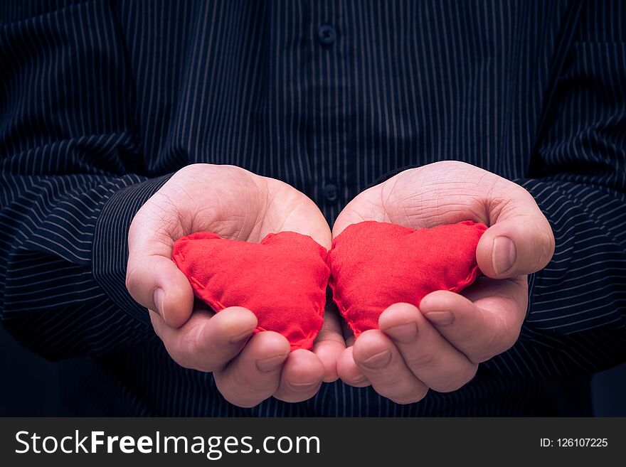 Two red hearts held in male hands