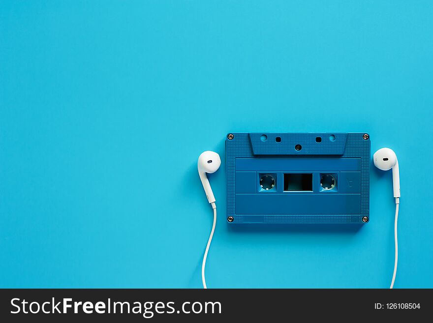 Retro cassette tape with earphones on blue background for music and relaxation concept